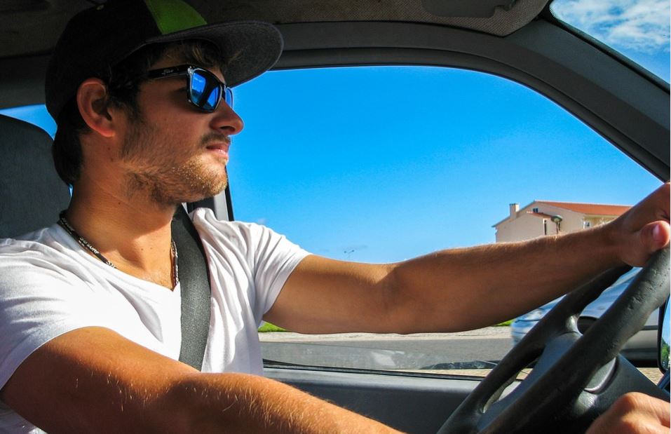 Chico joven conduciendo con gafas de sol.