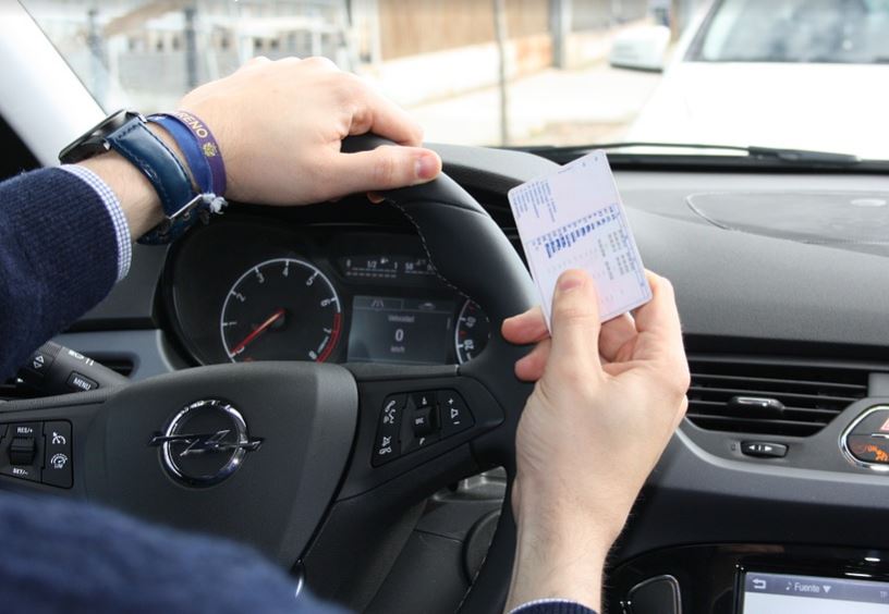 Conductor al volante sujetando el carnet de conducir.
