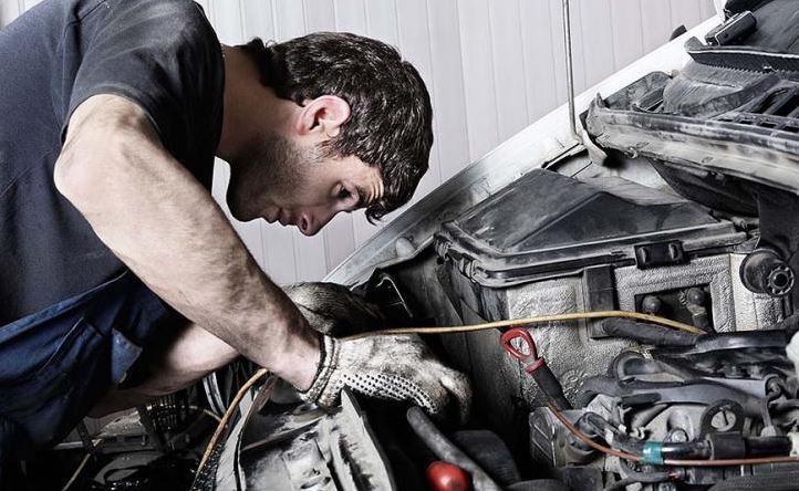 Un mecánico mirando un motor de un coche